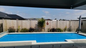 Ein rechteckiger Pool mit Holzlattenzaun und umlaufenden Pflanzen.