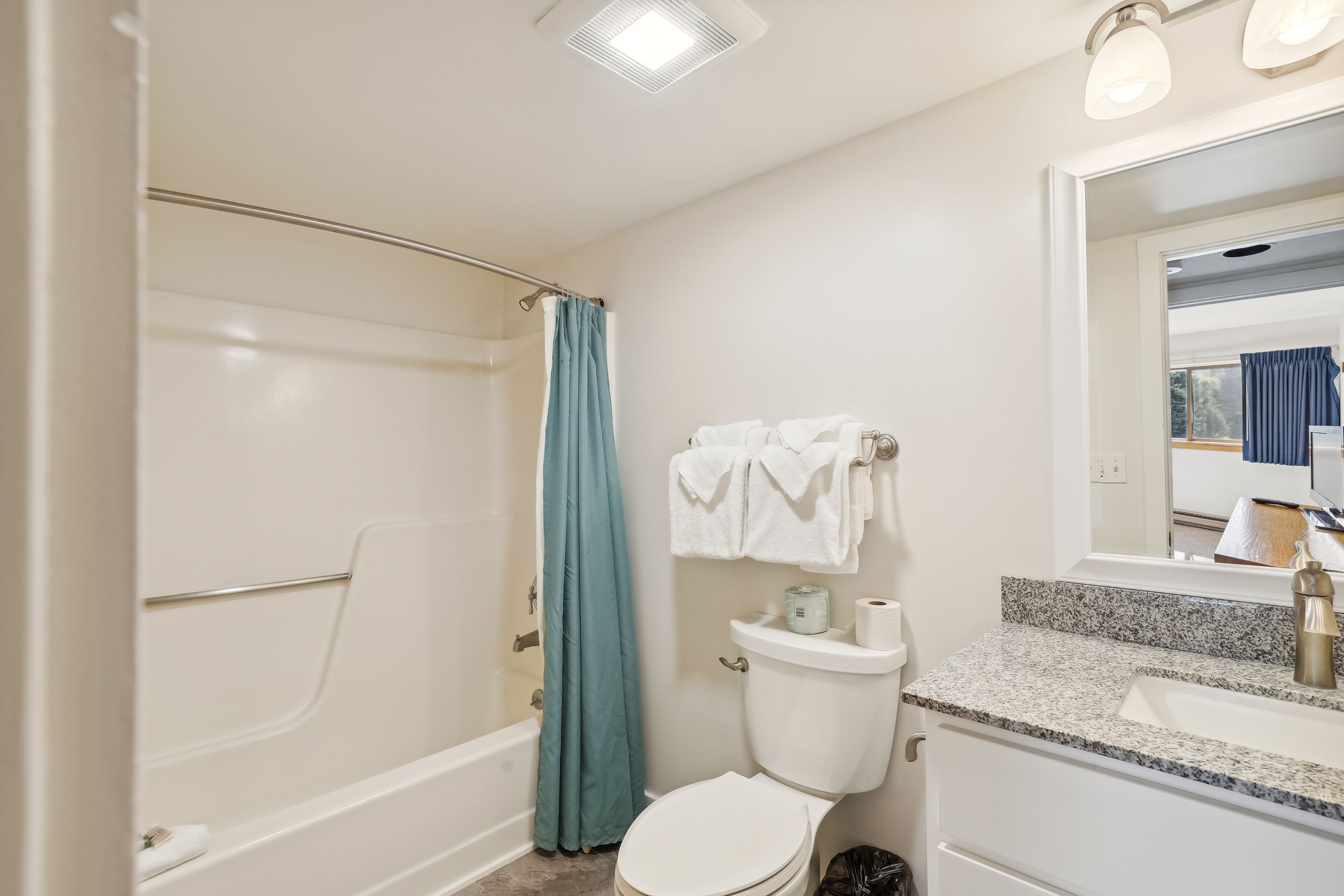 Un bagno con vasca, wc, lavandino e specchio.
