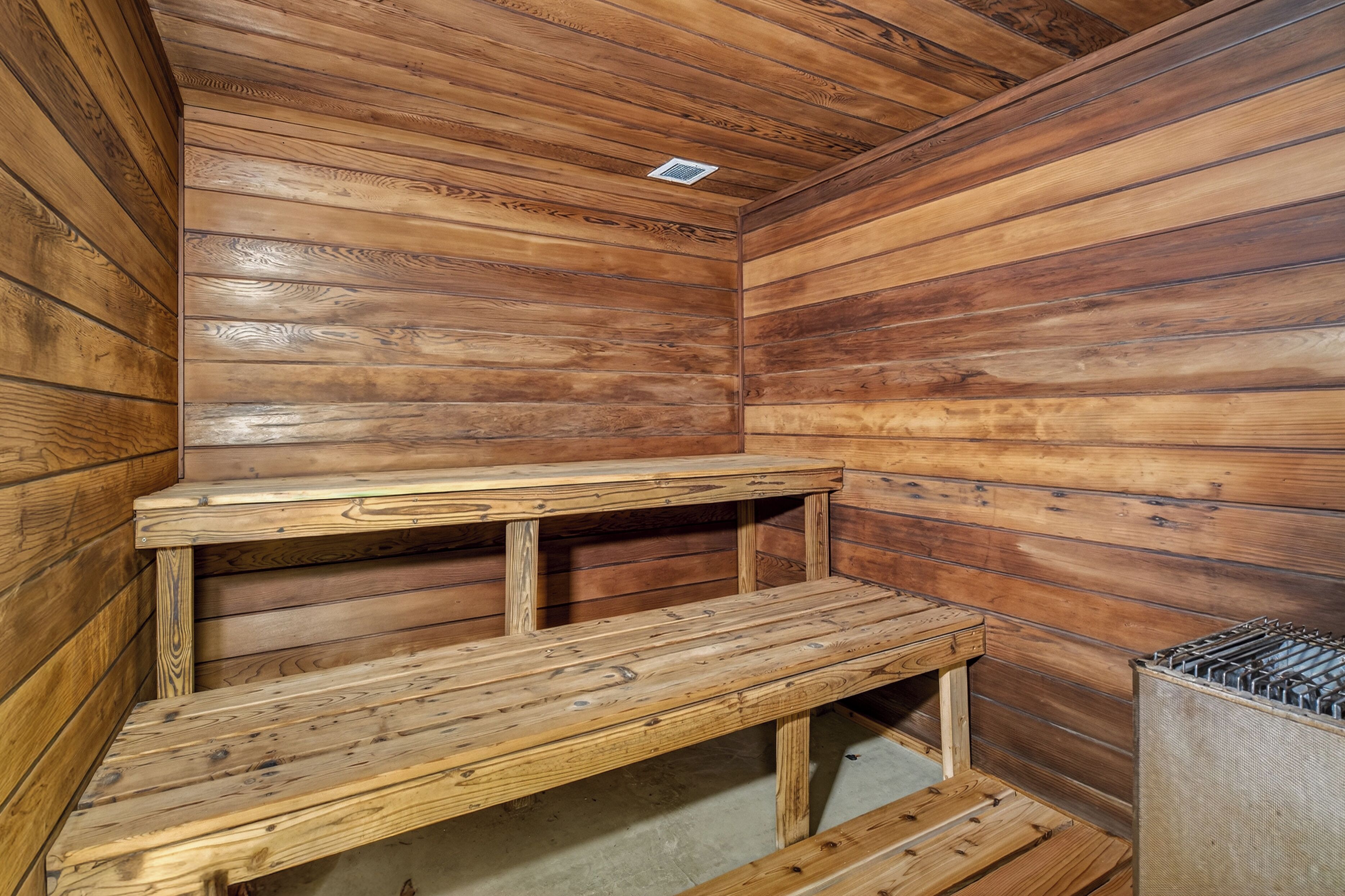 A wooden sauna room with benches and a ventilation system.