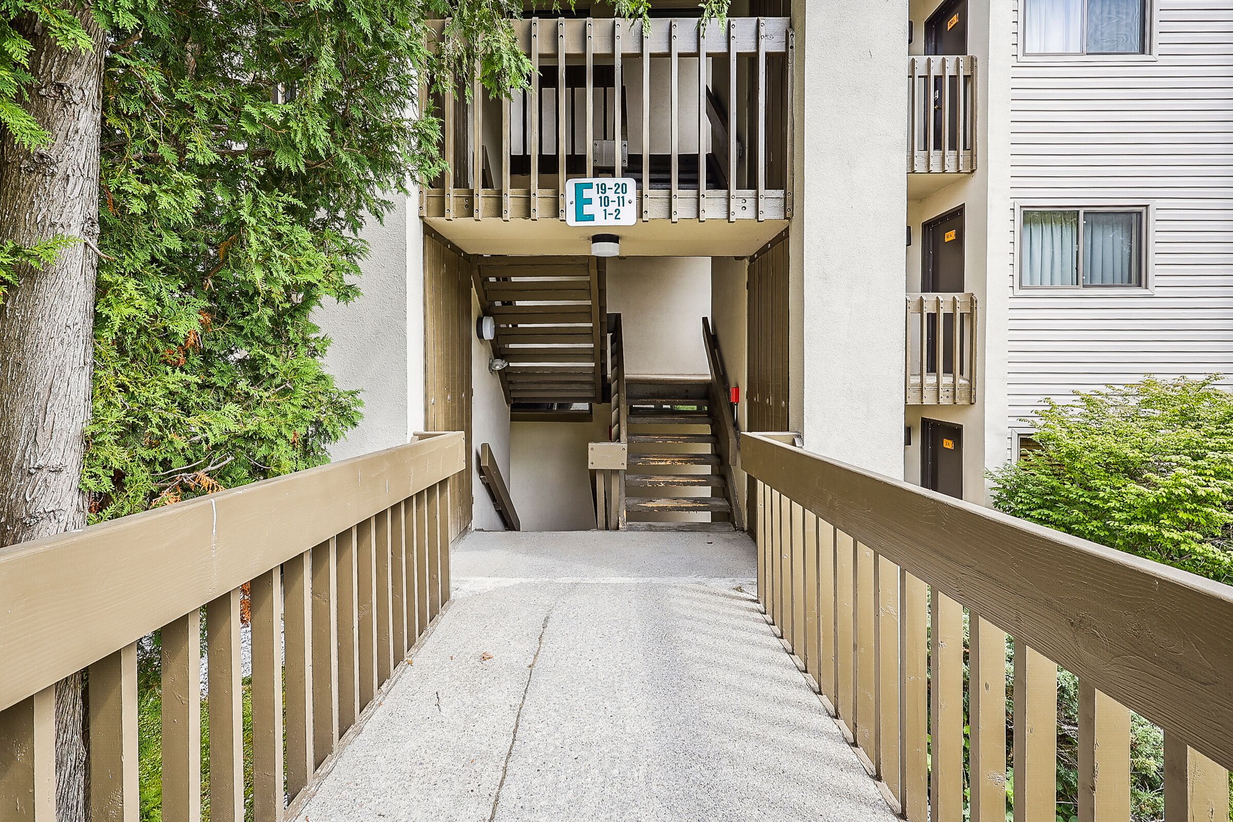 A concrete stairway leading to a building entrance with a wooden handrail.