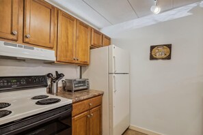 Compact kitchen with a microwave, stove, and refrigerator, perfect for everyday meals.