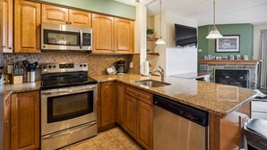 A modern kitchen with stainless steel appliances, wooden cabinets, and a granite countertop.