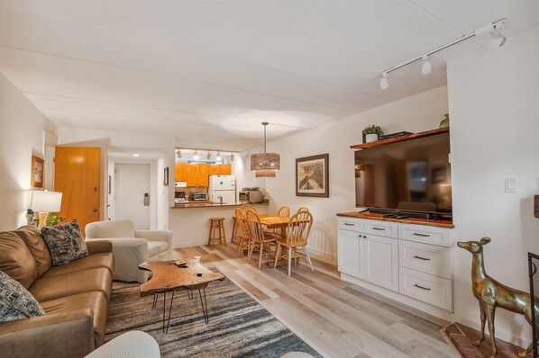 Relax in a spacious living room with a comfortable sofa, dining area, and kitchen.