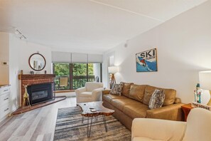 Cozy up by the fireplace in this stylish living room with a comfortable sofa set and a view of the outdoors.