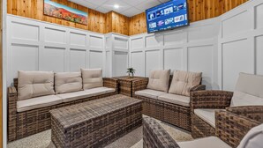 A room with a large sectional sofa, a small table, and wicker furniture. - Pinnacle Condo | Pool, Hot Tub | Golf Nearby A17 (Killington)