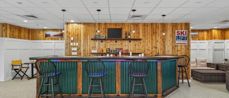 A bar area with a wooden wall, a counter, and three bar stools.