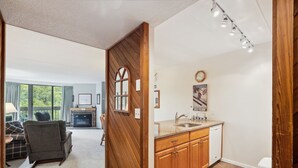 A modern kitchen with wooden cabinets, a sink, and a window. - Pinnacle F07 Renovated with granite counters offering shuttle to the slopes everyday of the week.  The outdoor pool, hot tub, and, tennis courts are open during summer only. (Killington)