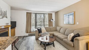 Un salon avec un canapé beige, une table basse, un téléviseur et une cheminée.