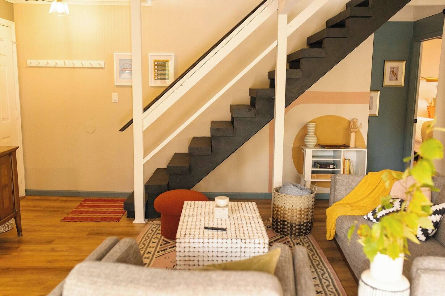 Un salon avec un escalier, un canapé, une table basse et une bibliothèque.