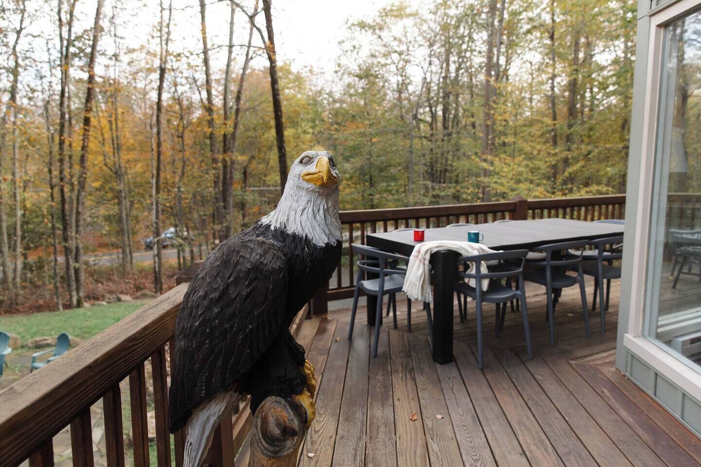 Une terrasse en bois avec une table et des chaises, donnant sur une zone boisée.