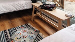 Une pièce confortable avec un lit superposé, une petite table sur laquelle est posé un jeu de société Cluedo, et une fenêtre donnant sur les arbres.