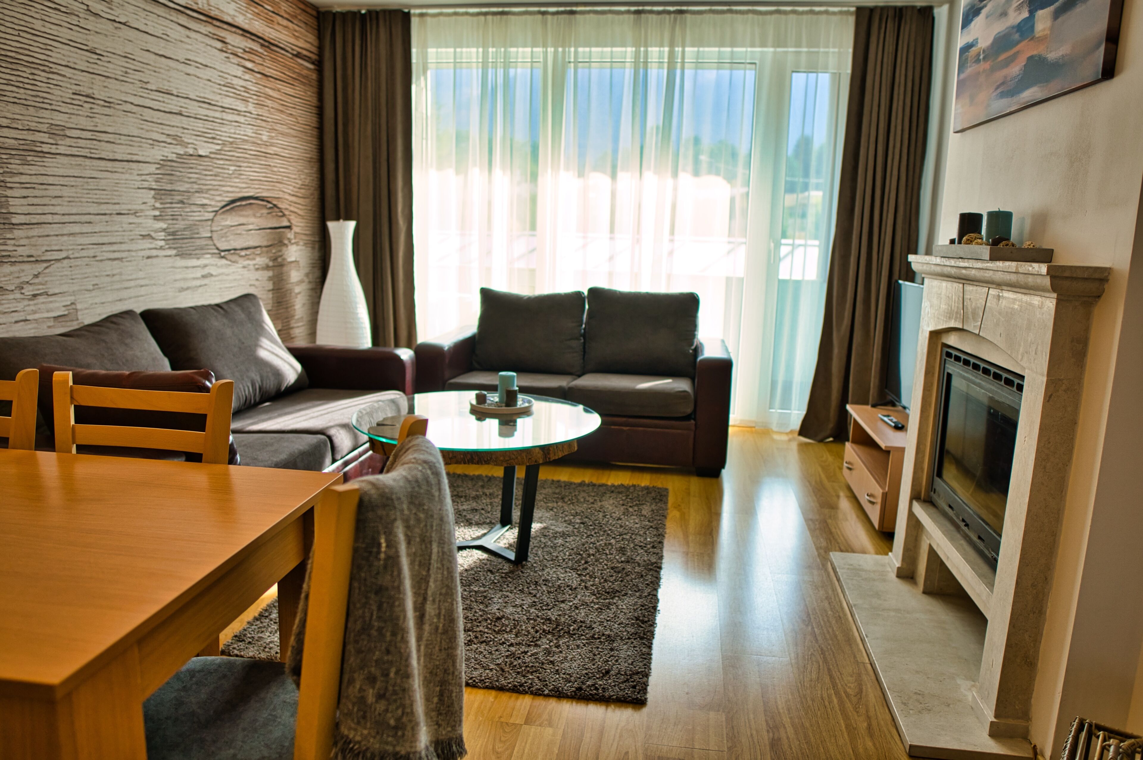 Ein Wohnzimmer mit einer Couch, einem Couchtisch, einem Kamin und Blick aus dem Fenster.
