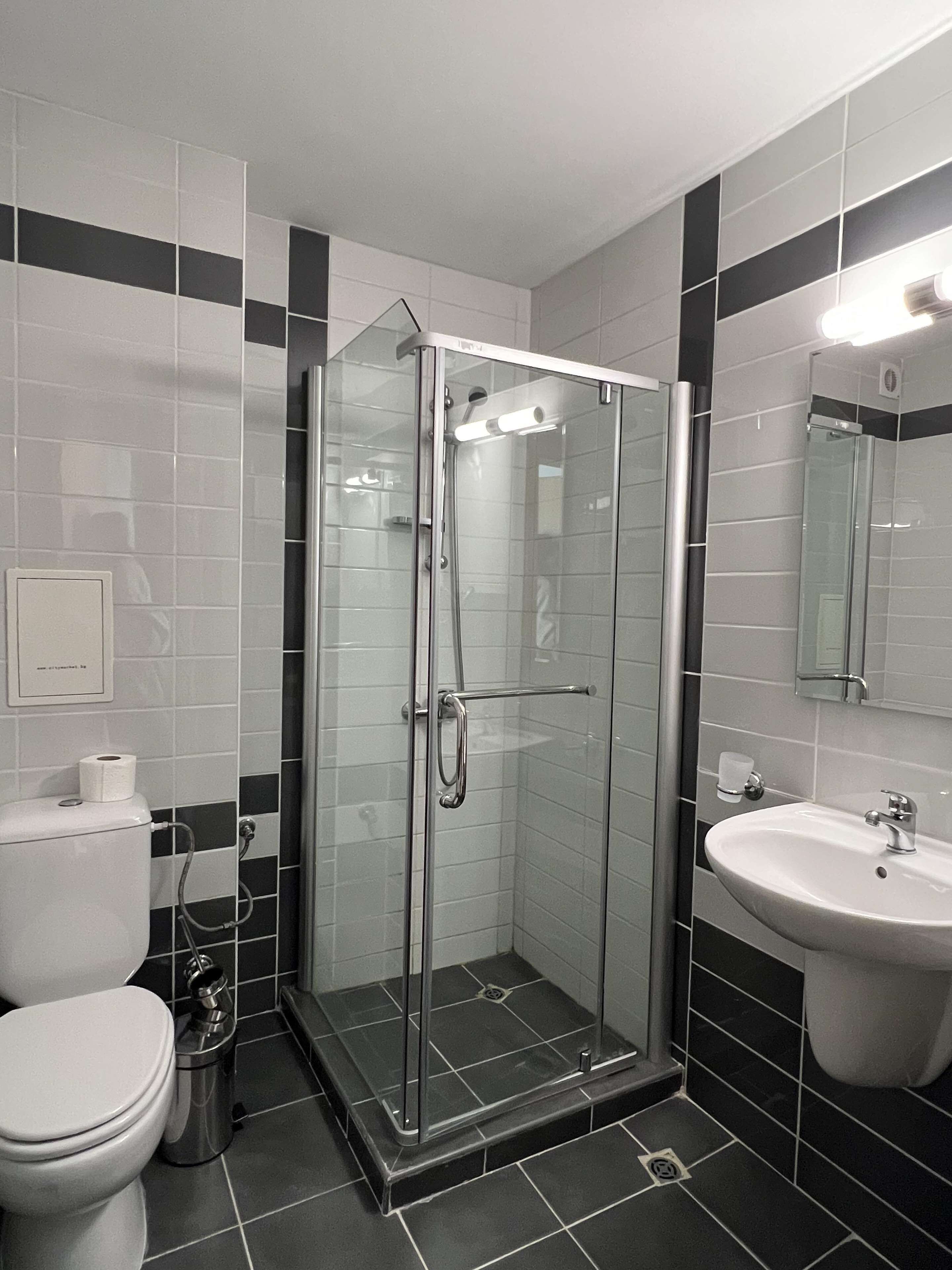 Une salle de bain moderne avec une douche à parois de verre, des toilettes blanches et un lavabo.