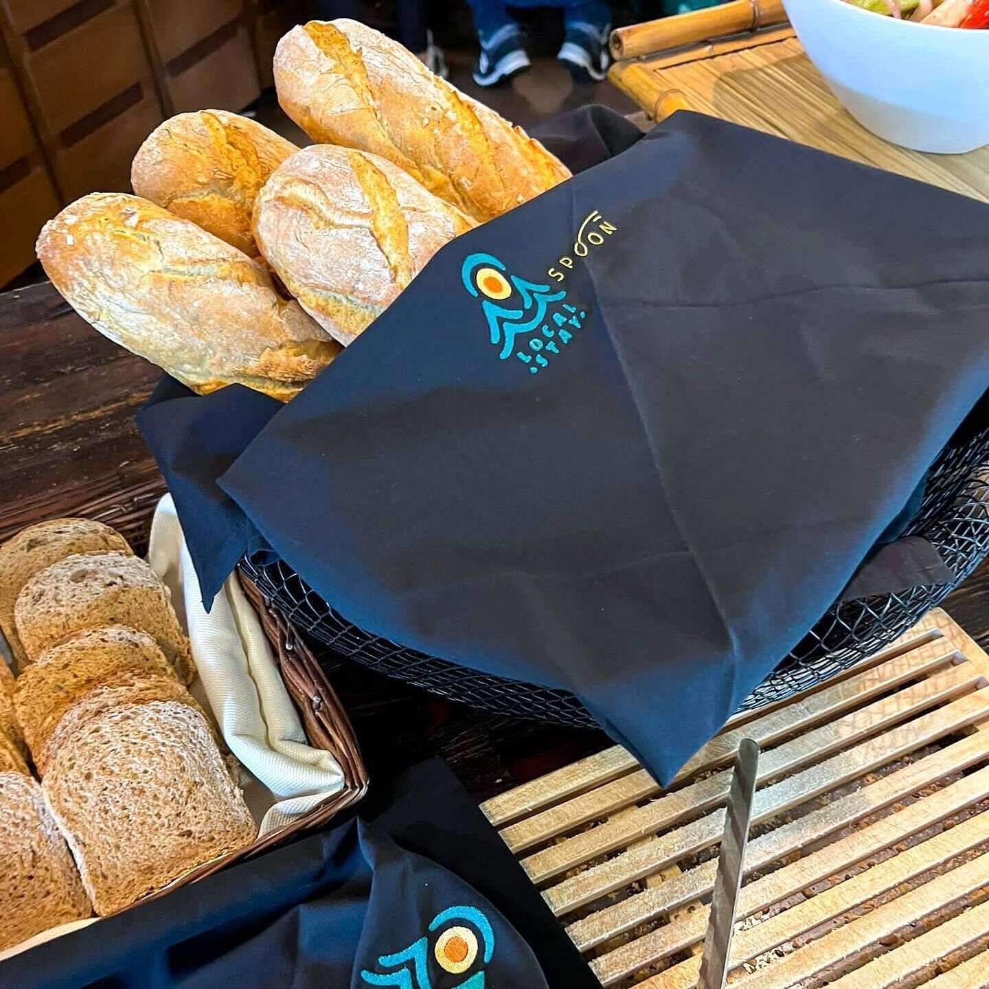 A basket of bread and a black bag with a logo.