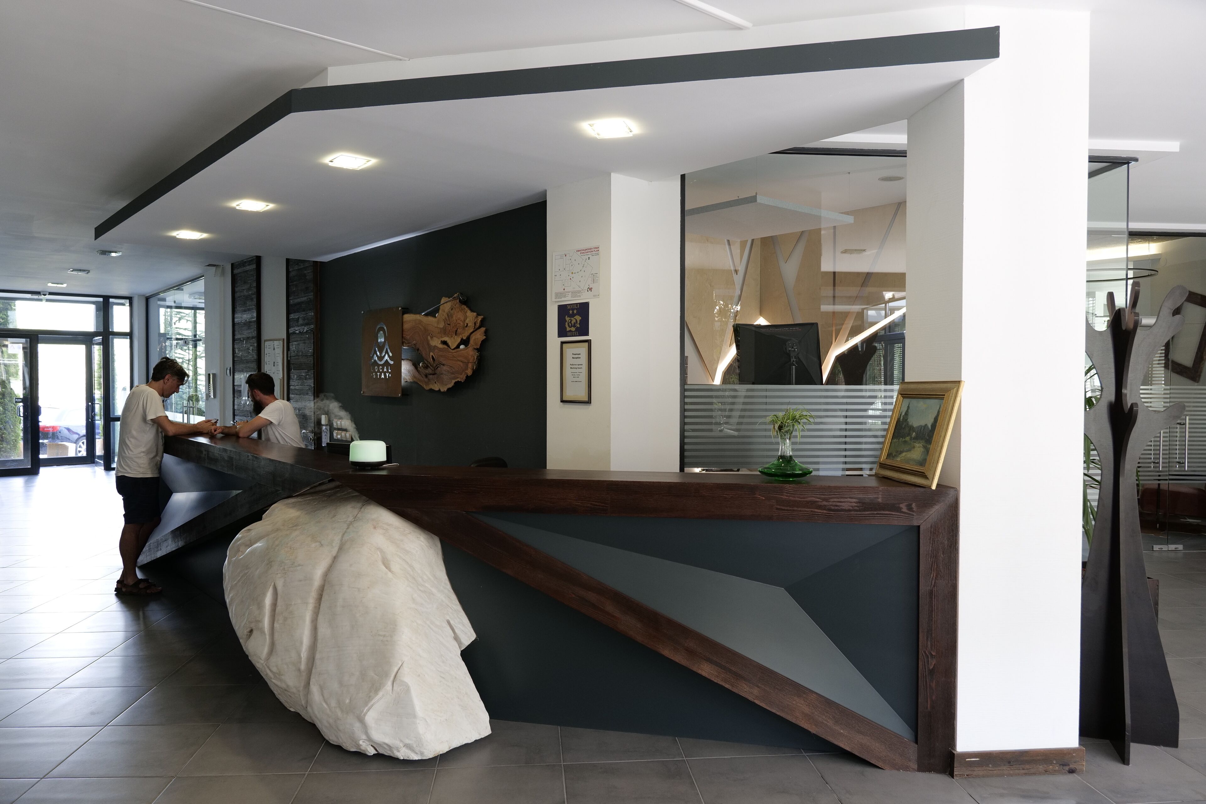 A reception desk with a modern design, a large abstract wall art piece, and a framed picture on the wall.