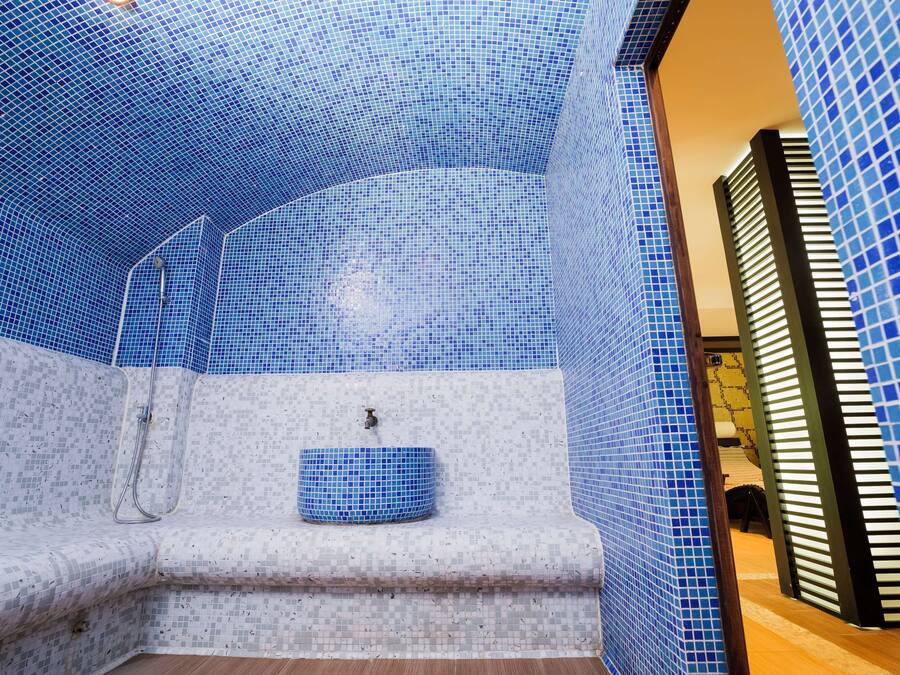Une salle de bain avec des carreaux de mosaïque bleus, une baignoire et un lavabo.