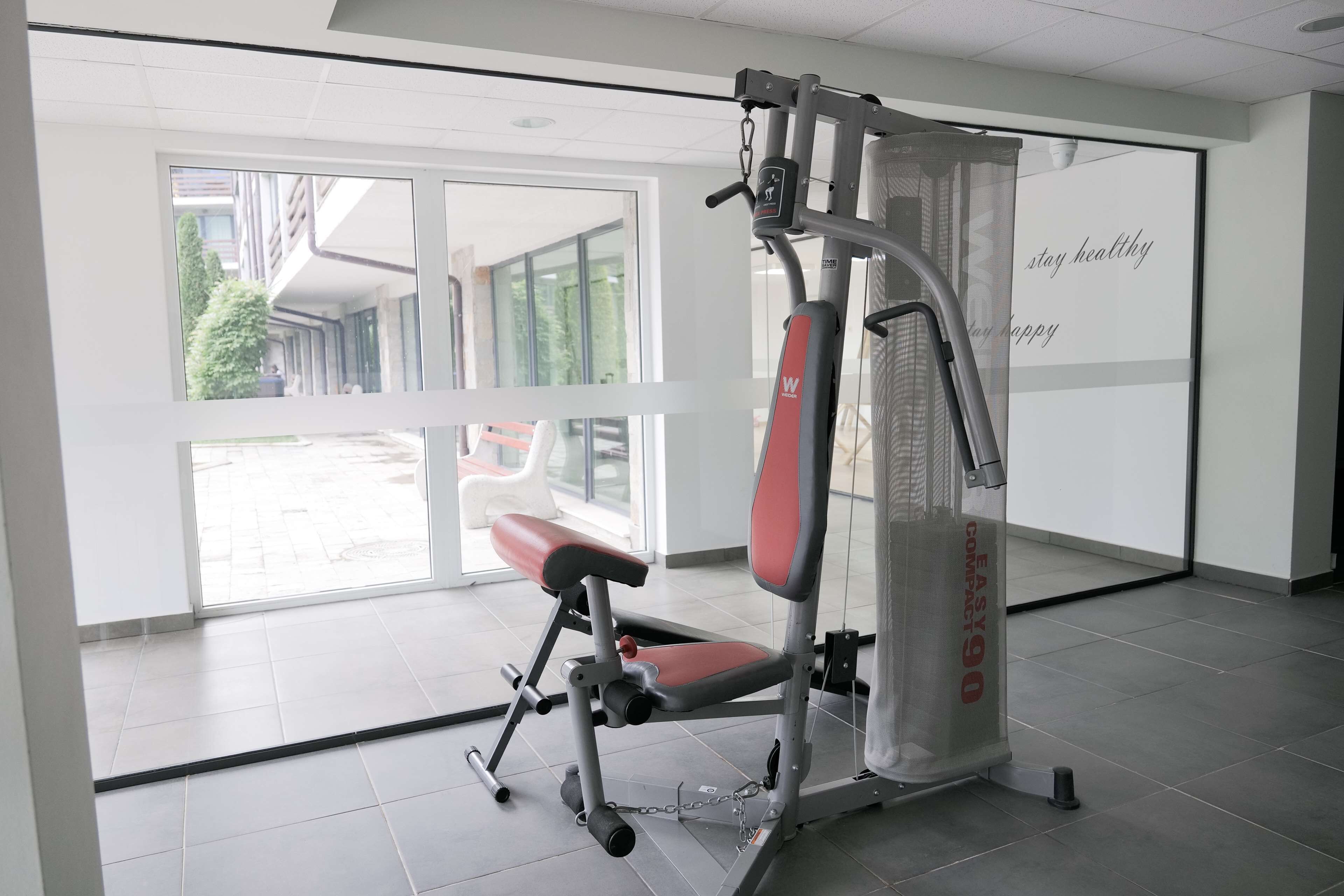 A gym with a stationary bike, a bench, and a wall with motivational text.
