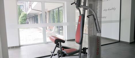 A gym with a stationary bike, a bench, and a wall with motivational text.