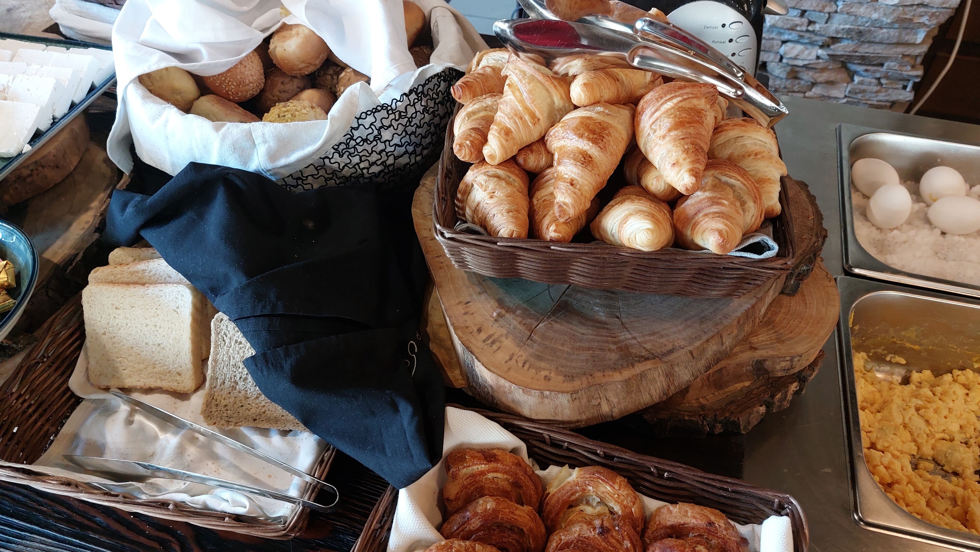 Buffet con diversos alimentos, incluyendo pan, pasteles y huevos.