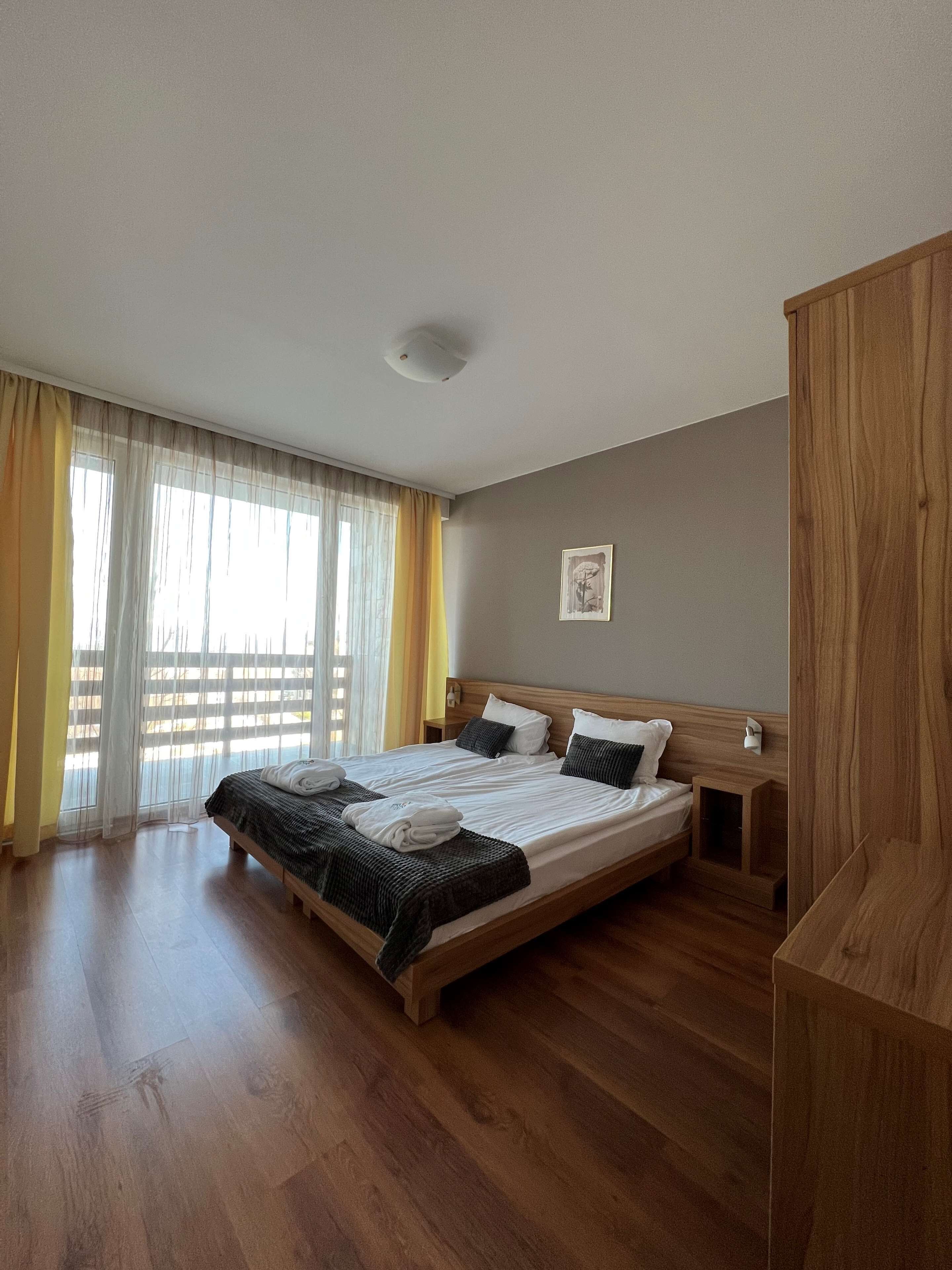 Quarto de hotel com uma cama grande, cabeceira de madeira e um guarda-roupa de madeira.