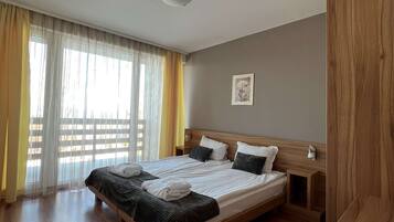 Quarto de hotel com uma cama grande, cabeceira de madeira e um guarda-roupa de madeira.