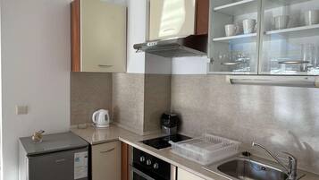 A compact kitchen with a refrigerator, oven, and built-in microwave.