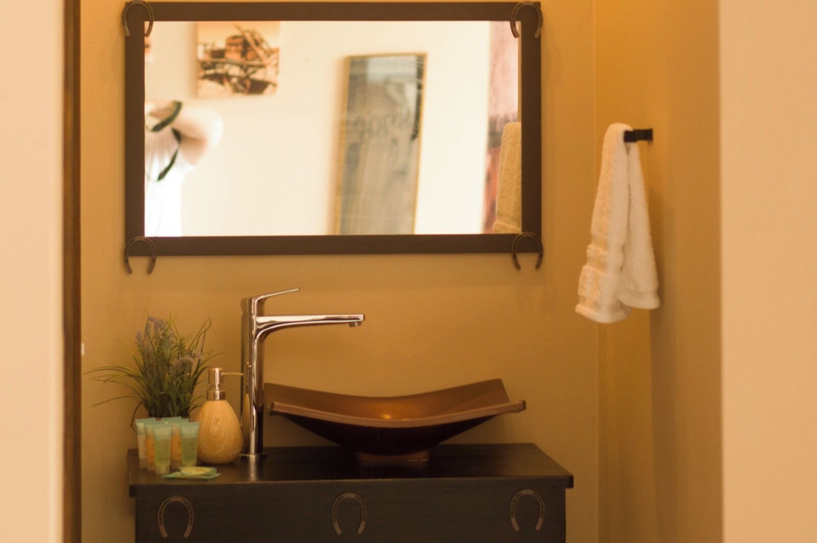 A bathroom vanity with a vessel sink, a mirror, and a towel rack.