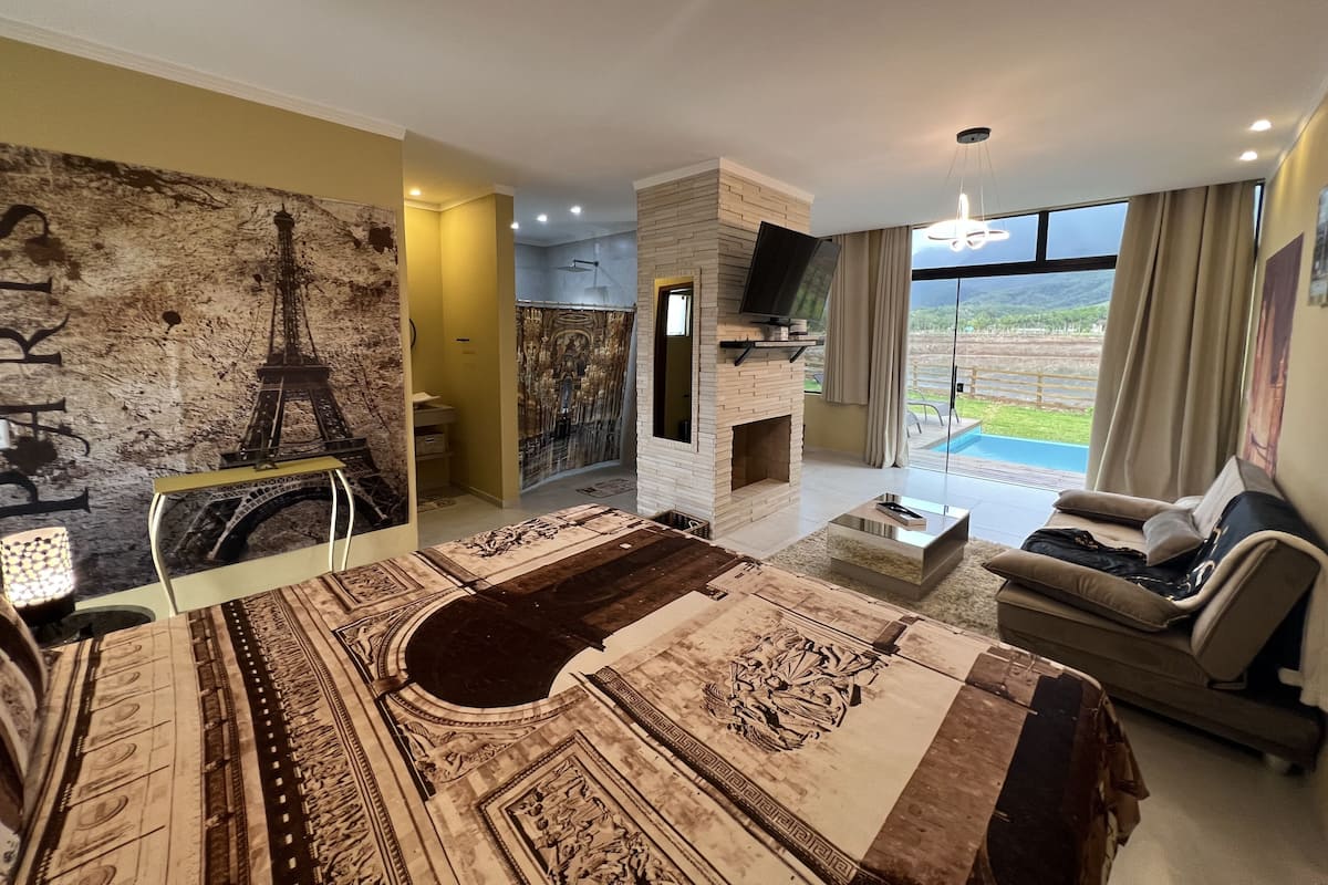 Un salon spacieux doté d’une grande fenêtre, d’une cheminée et offrant une vue sur l’extérieur.