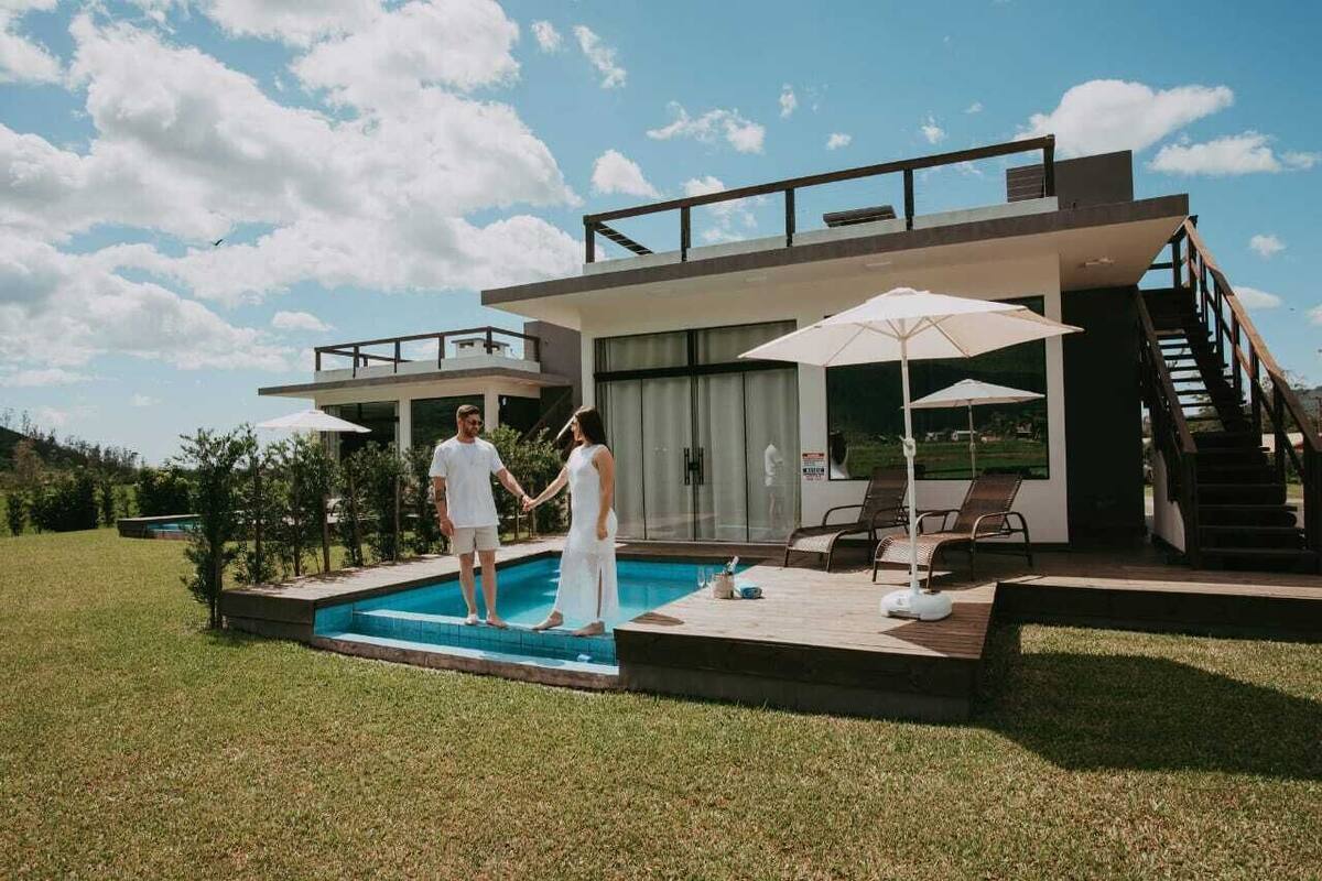 Une maison moderne dotée d’une piscine, d’un espace salon extérieur et d’un escalier menant à une terrasse.