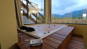 A wooden bench with a bathtub, a small table, and a window with a view of mountains.