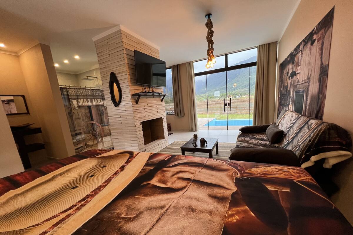 Un salon moderne avec une cheminée, un grand lit, un canapé et une vue sur l’extérieur.