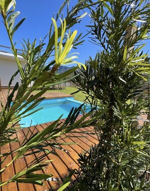 A wooden deck with a swimming pool, surrounded by greenery. - Pousada Green Canyons (Praia Grande)