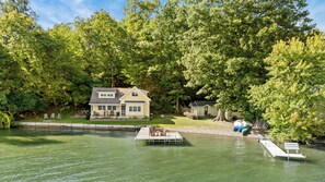 A lakeside house with a dock, surrounded by dense trees. - Crane Cove: 4 bedroom Lake Home on Keuka Lake (Penn Yan)