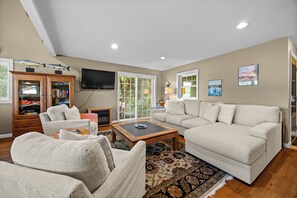 A living room with a sofa, armchairs, a coffee table, a fireplace, and a television.