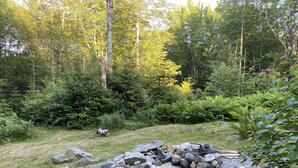 A forested area with a pile of rocks and a fire pit.