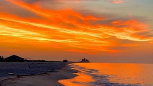 A beach at sunset with a clear sky and buildings in the distance. - Gulf Front Luxury-Extra Large Balcony-Regency Isle 907-Signature Properties (Orange Beach)