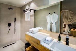 A modern bathroom with a large mirror, a wooden vanity, a shower area, and a towel rack.