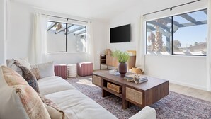Ein modernes Wohnzimmer mit einer Couch, einem Couchtisch und einem an der Wand montierten Flachbildfernseher.