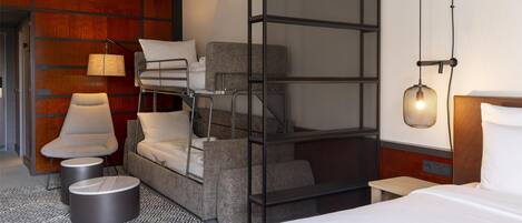 Una habitación de hotel moderna con una cama litera, un sofá, una silla y una mesita.