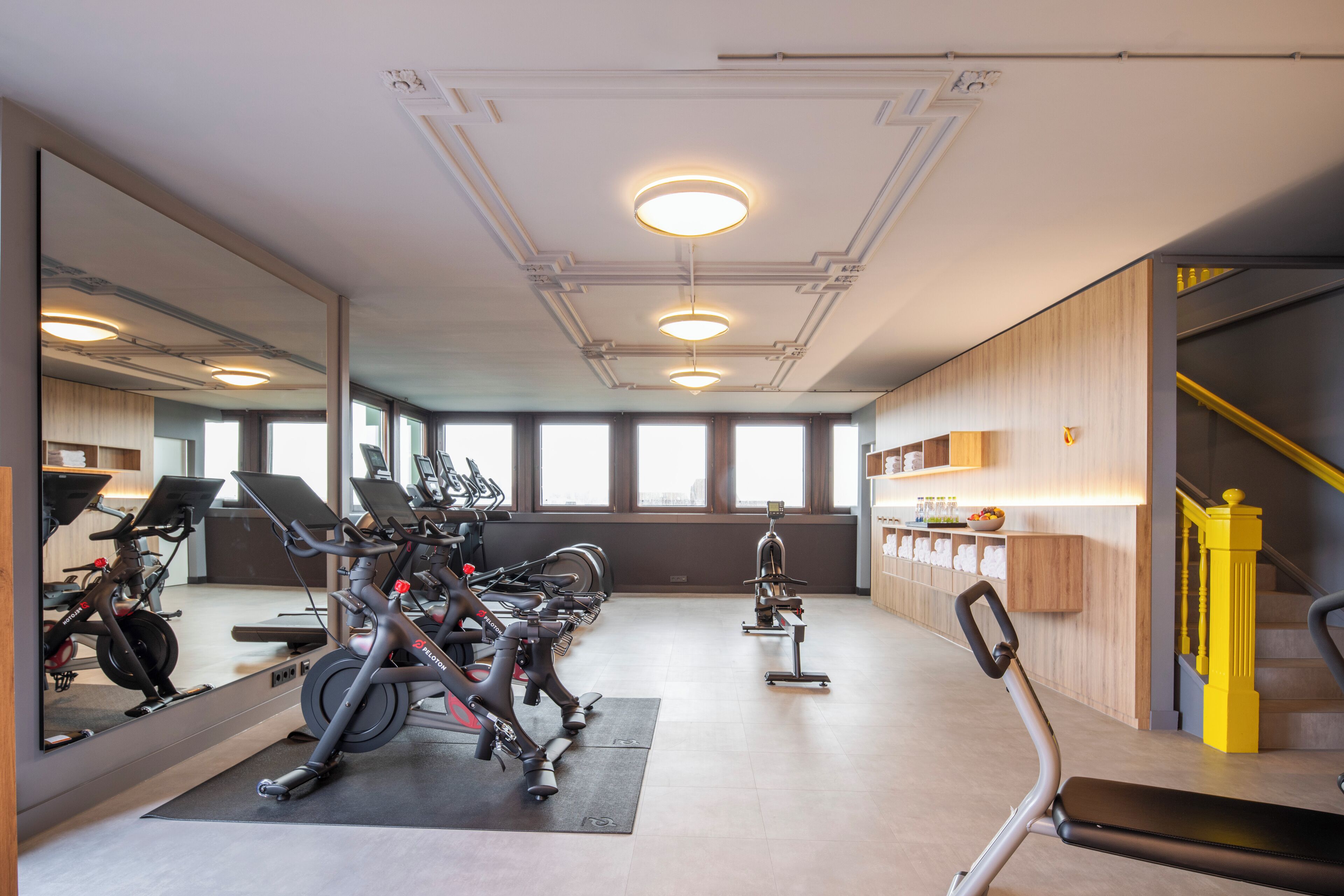 Ein Fitnessraum mit Trainingsgeräten, einem Spiegel und einer Treppe.