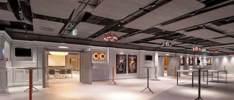 A spacious hotel lobby with modern furniture, a large chandelier, and a well-lit ceiling with exposed pipes.
