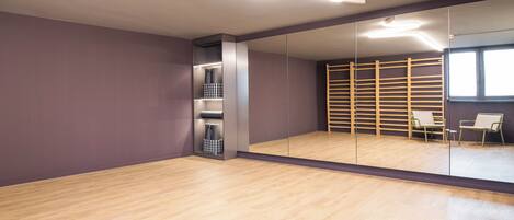 Una habitación moderna con un espejo grande, suelo de madera y estanterías integradas.