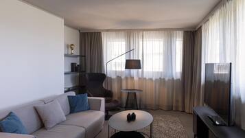 Una sala de estar moderna con sofá, sillón, mesa de centro, televisor y lámpara.