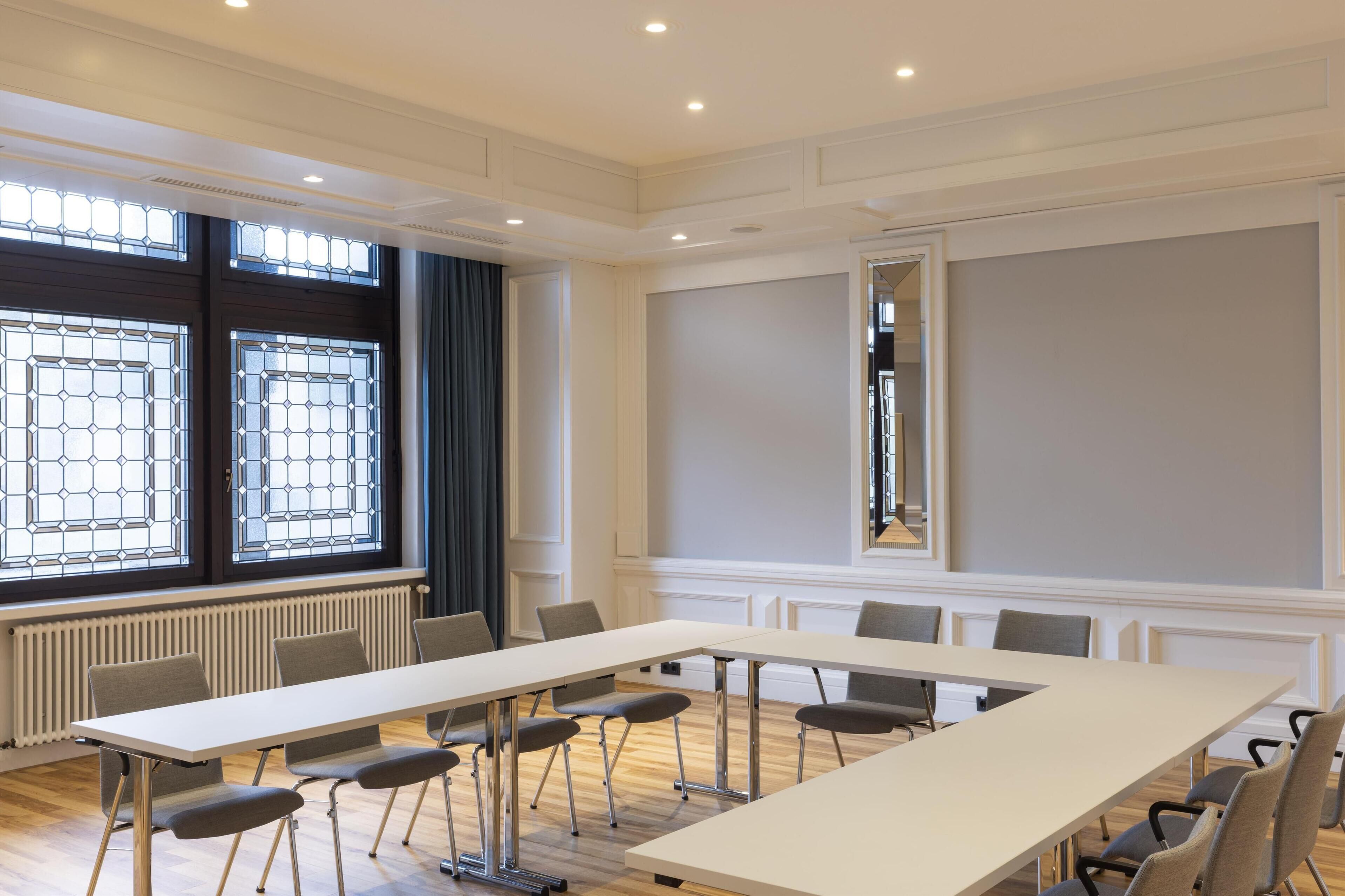 Een vergaderzaal met een lange tafel, stoelen en een groot raam met uitzicht.