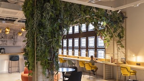 A modern bar area with a green wall, yellow chairs, and a large window. - Scandic Nürnberg Central (Nuremberg)