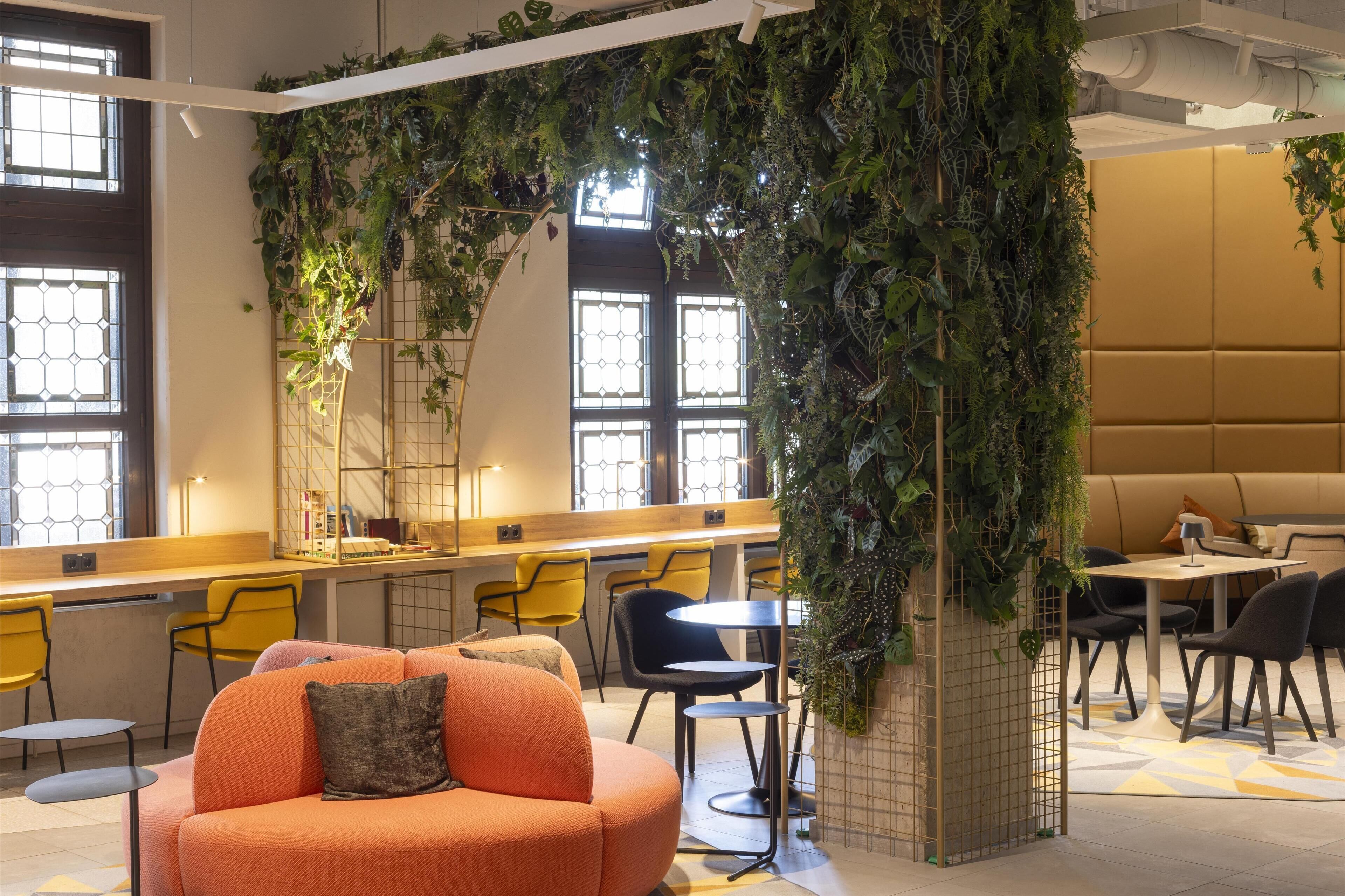 A modern indoor space with a seating area, a counter, and a large wall of greenery.