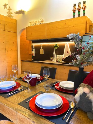 A dining area with a wooden table set for a meal, a vase with flowers, and a nutcracker figurine on the wall.