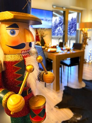 Une figurine de casse-noisette dans une pièce où l’on aperçoit une table en bois et un téléviseur au fond.