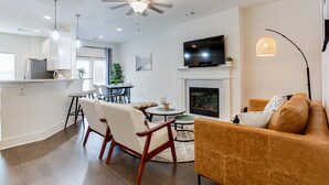 A modern living room with a fireplace, a television, and a dining area with chairs and a table. - ❤ of Stonecrest☀1556ft²☀Backyard☀Parking☀W/D (stone crest)