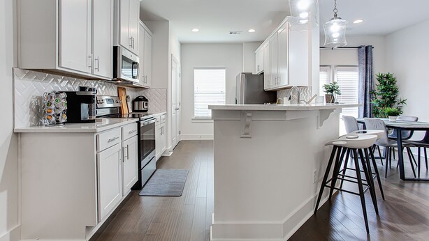 A modern kitchen with white cabinets, stainless steel appliances, and a central island with bar stools. - ❤ of Stonecrest☀1556ft²☀Backyard☀Parking☀W/D (stone crest)